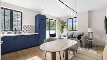 Una cocina moderna con armarios azul oscuro, una mesa de comedor de mármol y un ventanal grande.