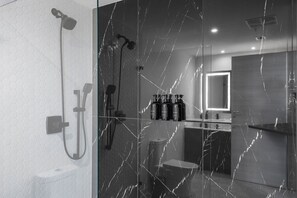 Un baño moderno con cabina de ducha de vidrio, pared de azulejos hexagonales y suelo con diseño de mármol.