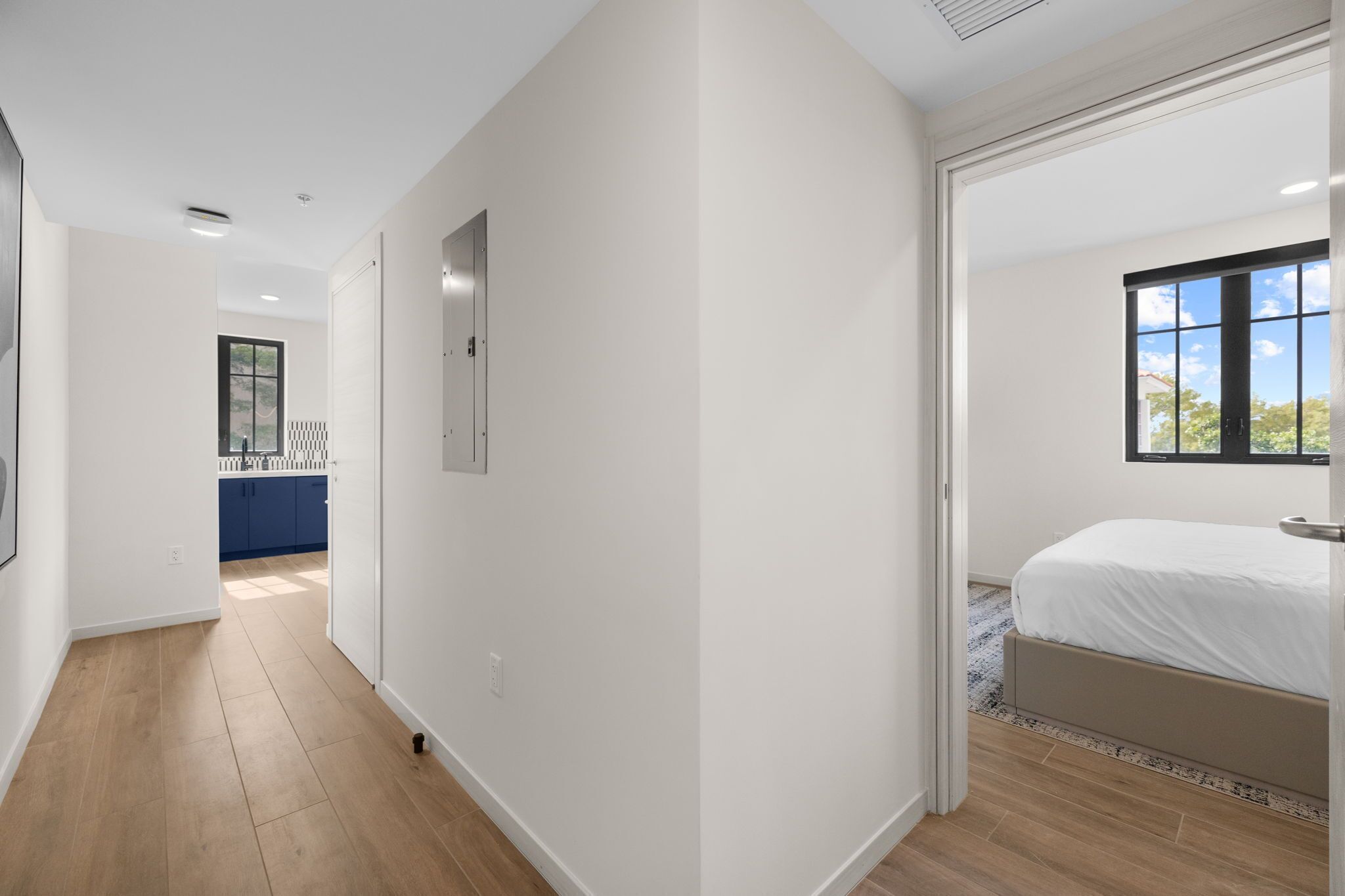 A modern bedroom with a large bed, a view of the outdoors through a window, and a separate bathroom area.
