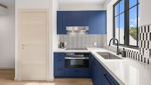 Una cocina moderna con horno empotrado, campana extractora de acero inoxidable y un ventanal que proporciona luz natural.