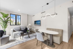 A modern living room with a sofa, coffee table, and dining area.