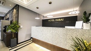 A hotel reception desk with a modern design, a sign reading 'HOTEL DUBAI,' and a potted plant. - Dubai Hotel Dangjin (Dangjin)