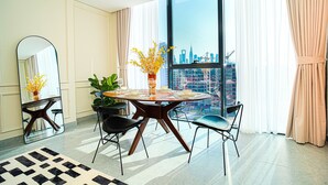 Un comedor moderno con una mesa redonda, sillas, un espejo y vistas a la ciudad.