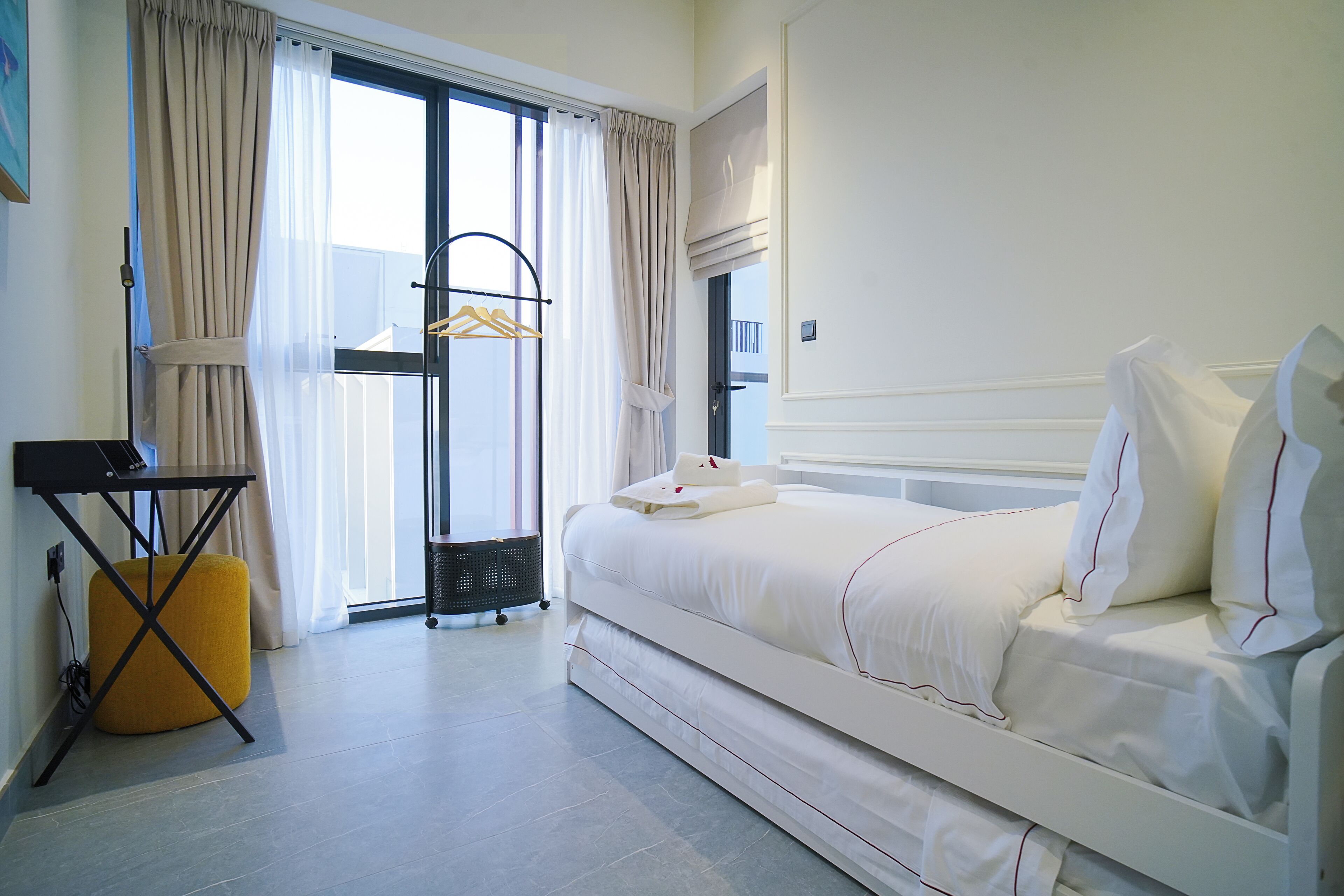 A hotel room with a bed, a desk, and a window with curtains.
