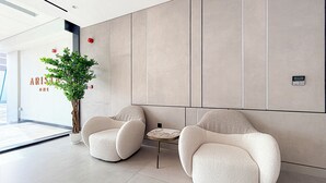 Un área de espera moderna con dos sillones cómodos, una mesita y una planta en maceta.