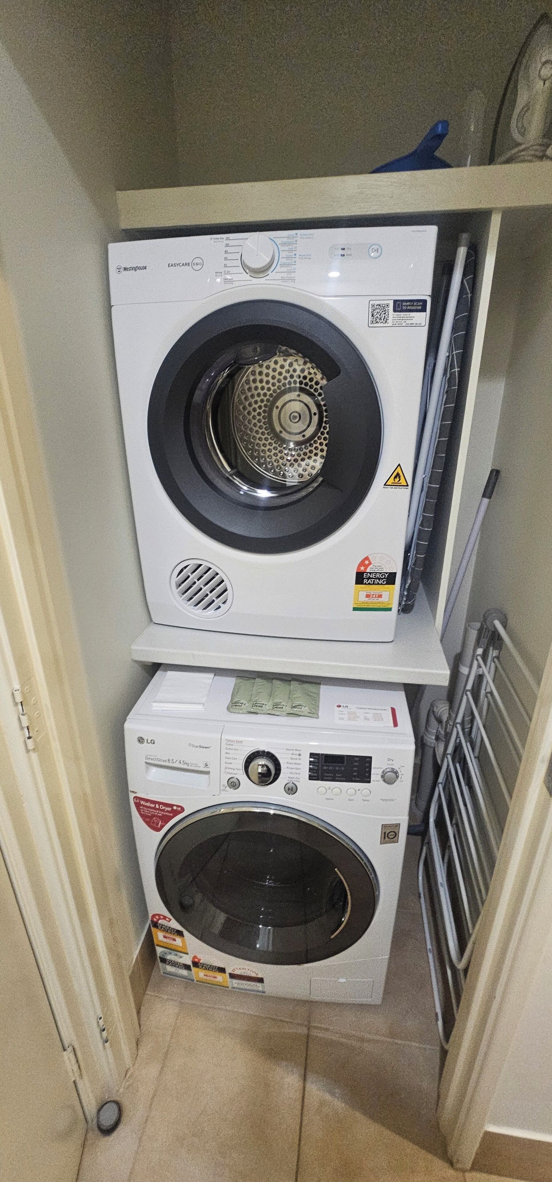 A compact laundry area with a front-loading washing machine and a stacked dryer.