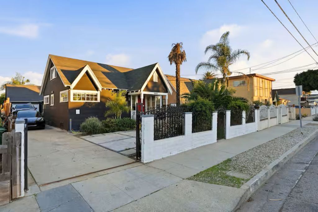 A residential house with a front yard, a driveway, and a gated entrance.