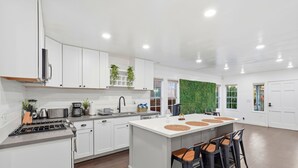 Een moderne keuken met witte kasten, een centraal eiland met krukken, en een groene wand.