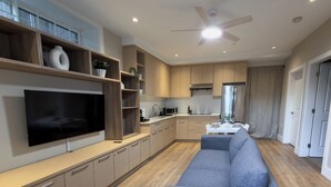En moderne stue med et stort fladskærms-tv, en sofa og et spiseområde med et bord og stole.