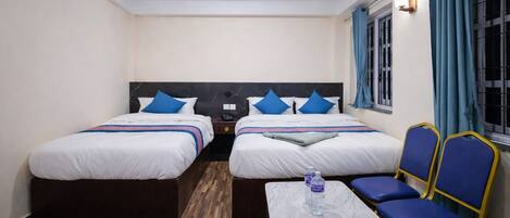 A hotel room with two beds, a small table, and two chairs.