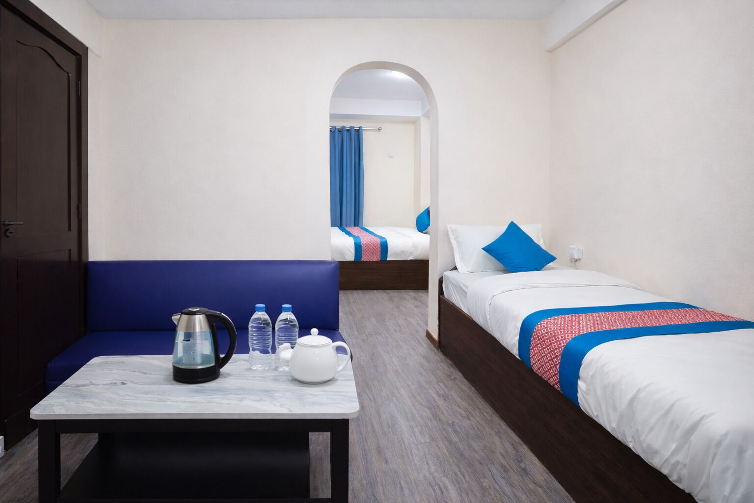 Una habitación de hotel con una mesa de mármol, dos camas, un sofá y una kitchenette.