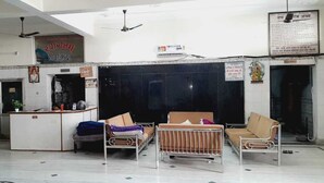 A reception area with a counter, chairs, and a large dark wall. - BABA SITARAM ASHRAM (Haridwar)