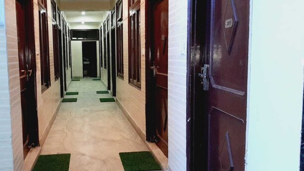 A corridor with doors on both sides, green carpets, and a tiled floor. - BABA SITARAM ASHRAM (Haridwar)