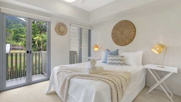A bedroom with a bed, a bedside table, a lamp, and a view of the outdoors. - Distinct at the Botanicals (Edge Hill)
