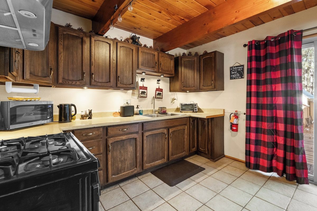 Una cocina con armarios de madera, estufa, microondas y cafetera.