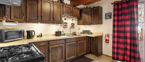 A kitchen with wooden cabinets, a stove, a microwave, and a coffee maker.