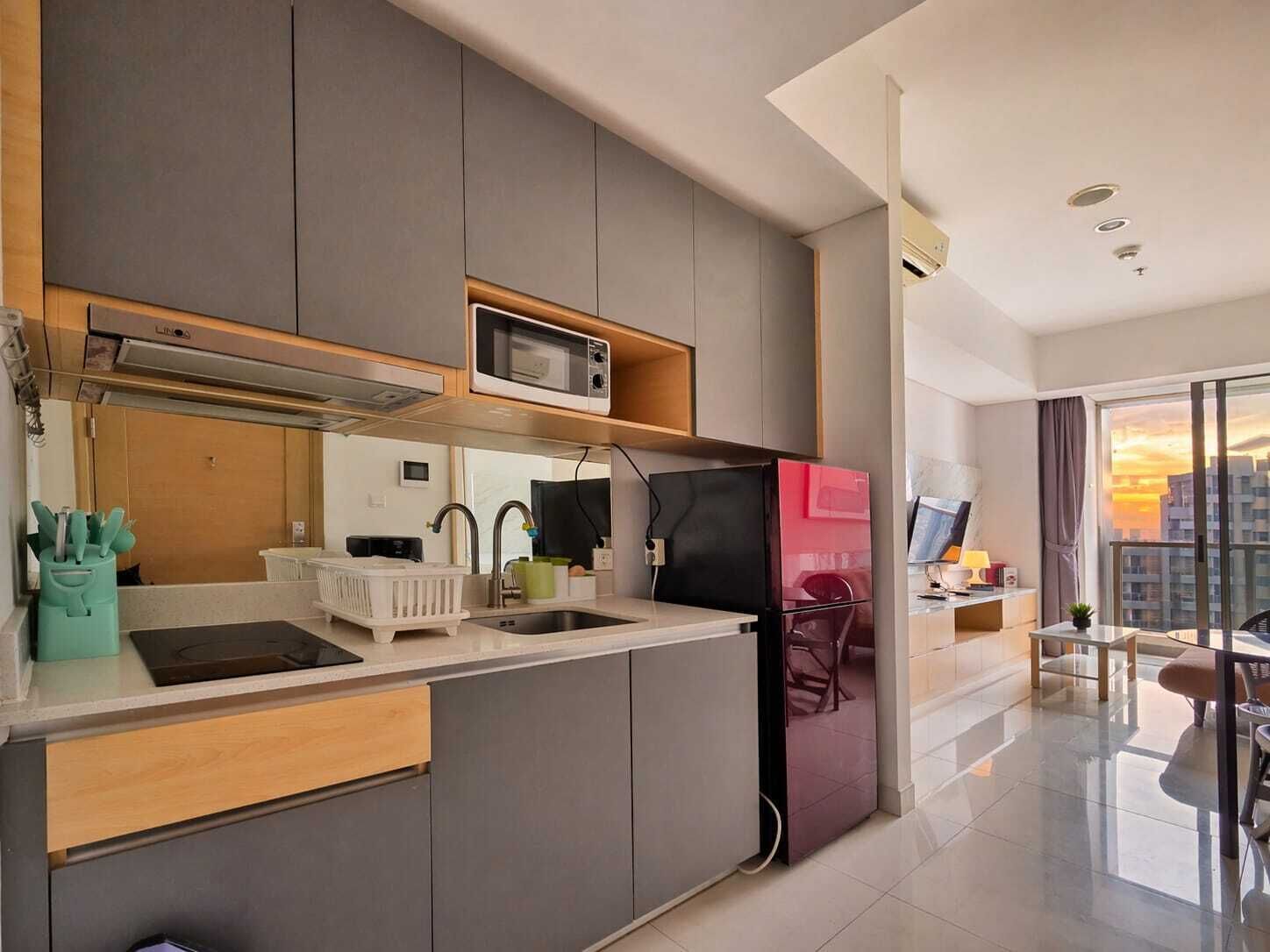 A modern kitchen with grey cabinets, a black refrigerator, a microwave, and a sink.