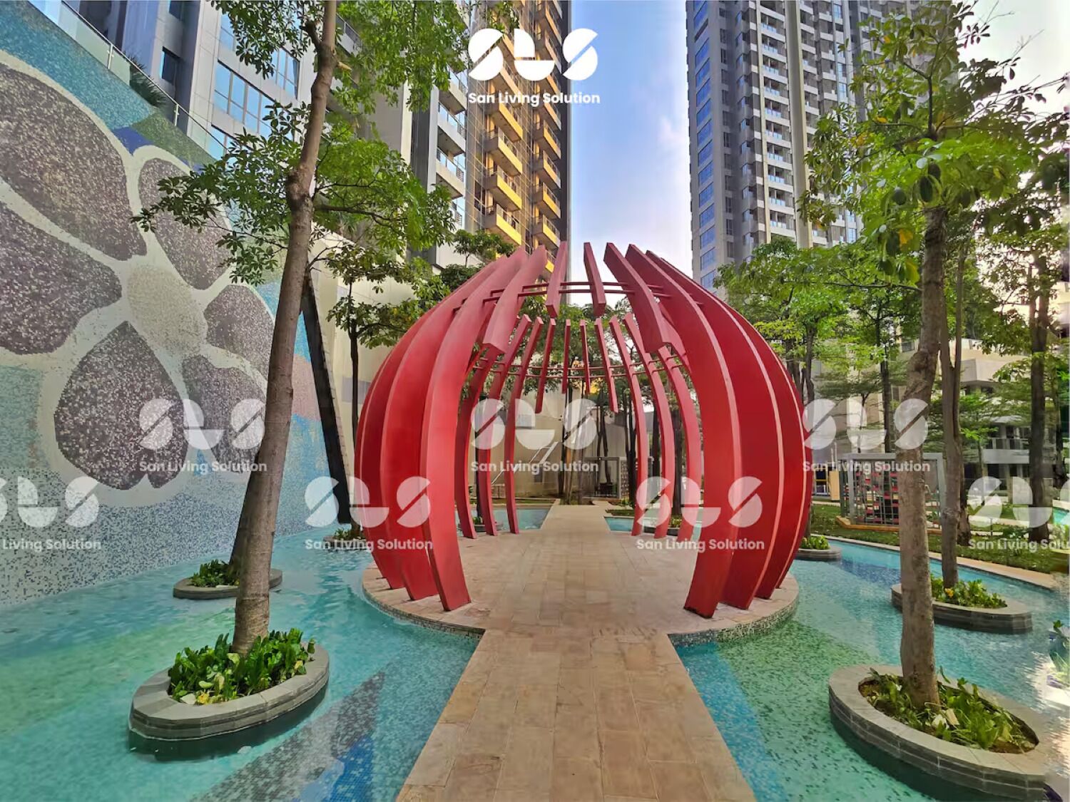 A modern outdoor area with a central red sculpture, surrounded by trees and a pool.