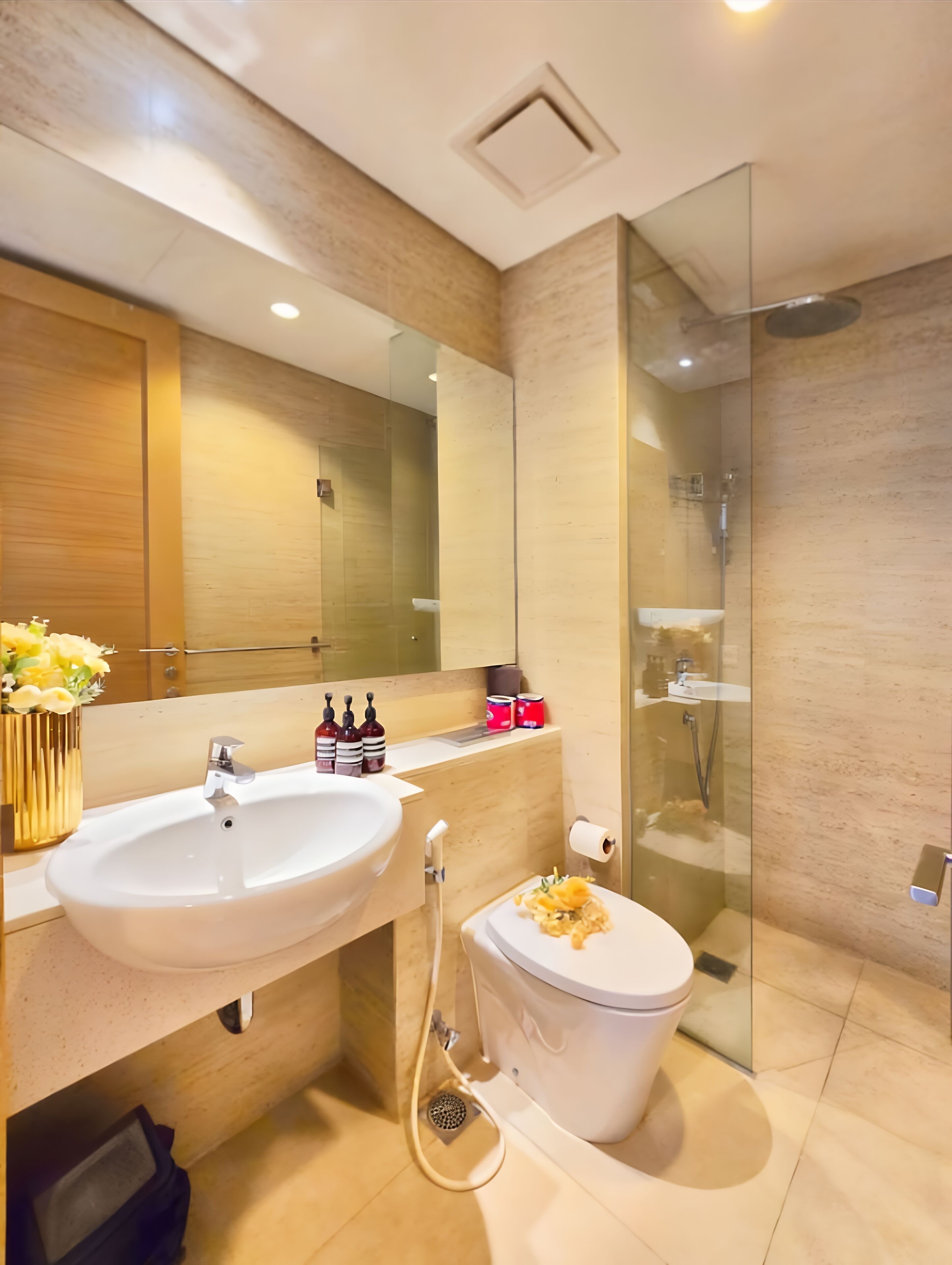 A modern bathroom with a large mirror, a sink, and a toilet.