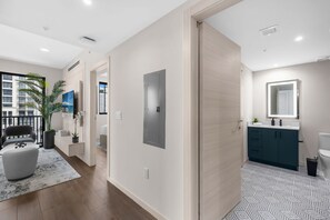 Eine moderne Wohnung mit Wohnbereich, einem Badezimmer mit großem Spiegel und Blick auf ein Gebäude.