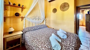 A bedroom with a bed, a nightstand, a lamp, a canopy bed, and decorative wall items. - Apartment in Galapagar With Pool and Garden (Galapagar)