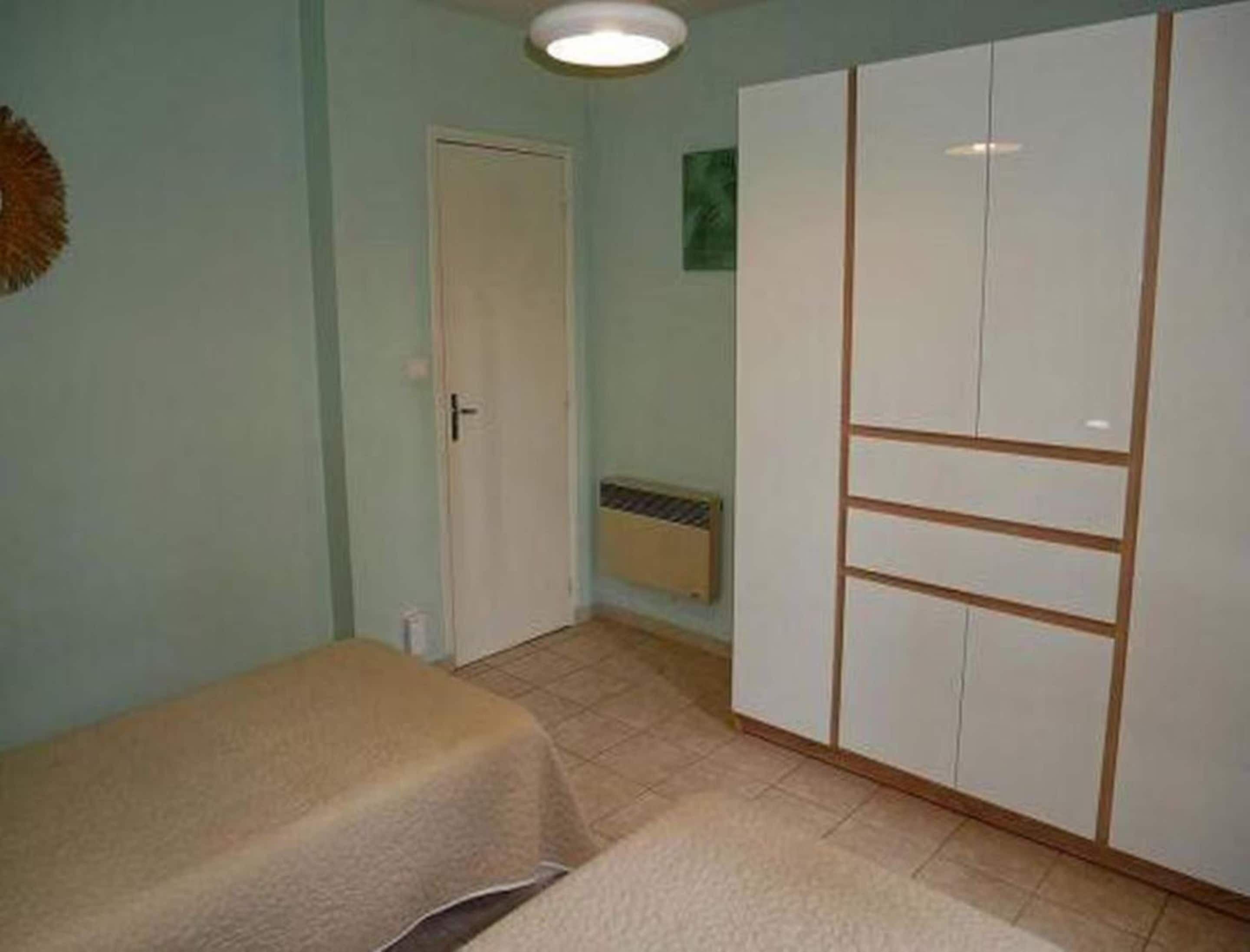 Une chambre à coucher avec un lit, une armoire et une porte.