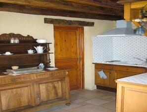 A kitchen with wooden cabinets, a white tiled backsplash, and a wooden door. - Pleasant Holiday Home in Salviac With Swimming Pool (Salviac)