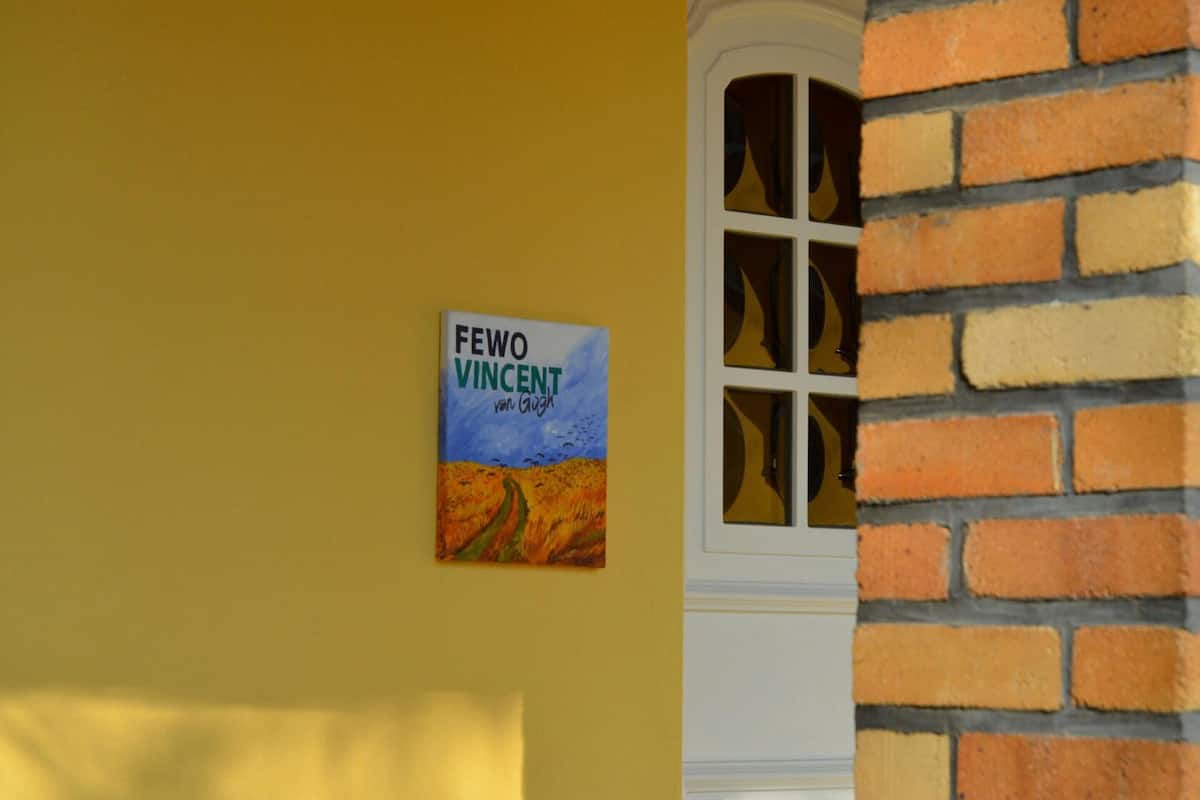 Een boek met de titel 'Fewo Vincent' van Van Gogh op een gele muur.
