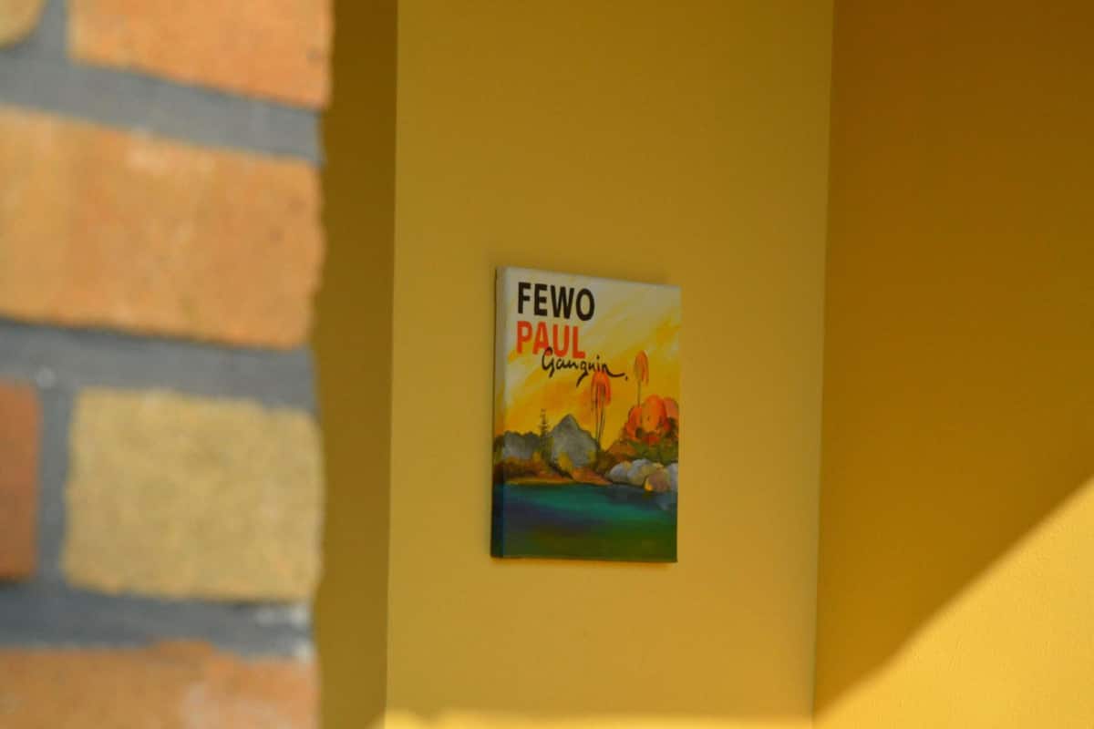 Een bord met de tekst 'FEWO PAUL' bevestigd aan een gele muur.