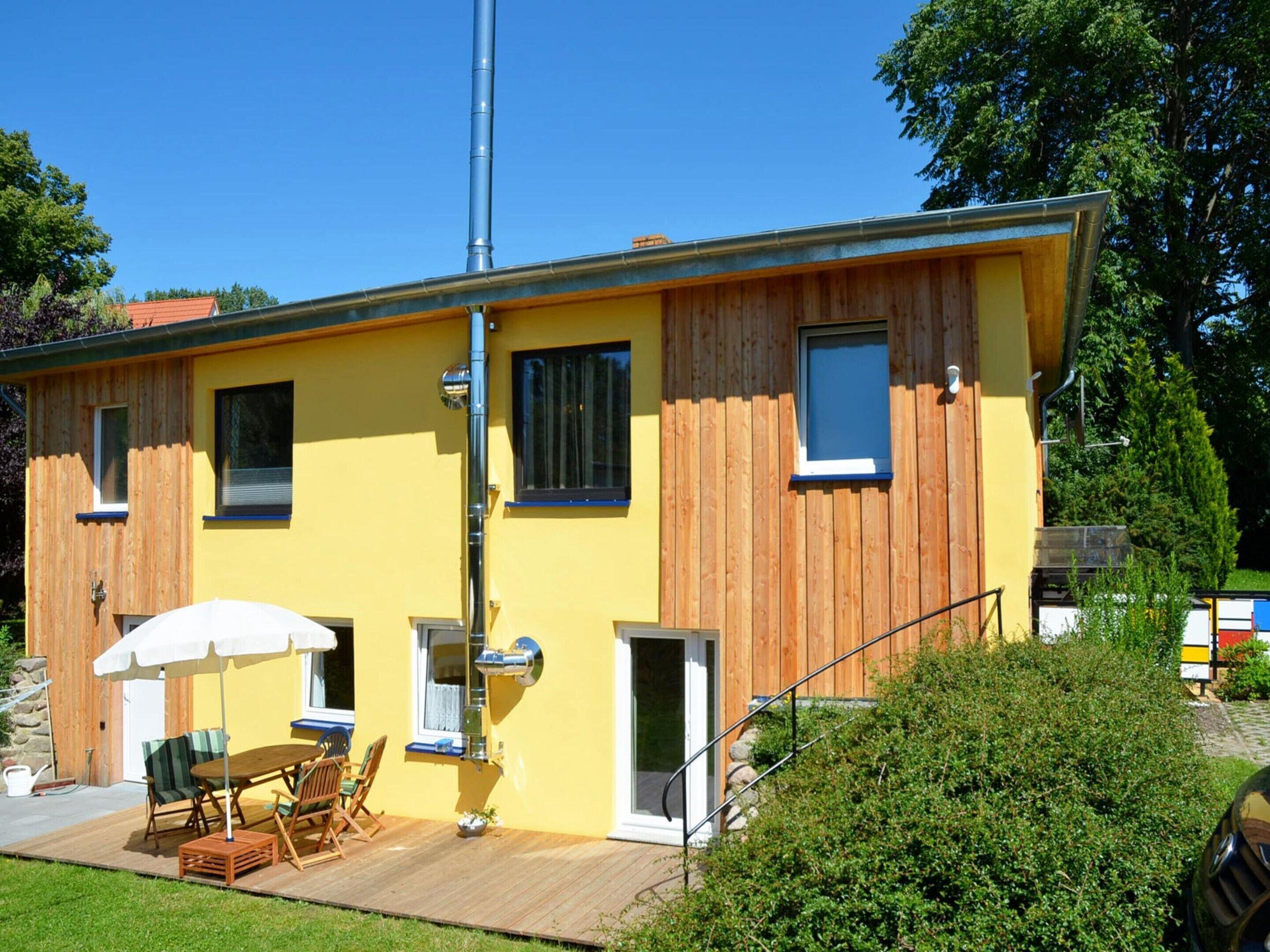 A yellow building with wooden accents, a deck with outdoor furniture, and a covered patio area.