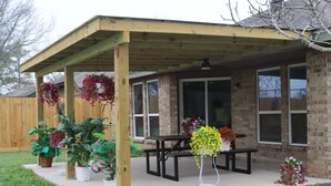 A covered patio with a wooden pergola, a picnic table, and potted plants. - Peaceful Retreat  Near NASA & Kemah 3BR/2BA (Houston)