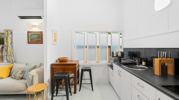 A modern kitchen with white cabinets, a black countertop, and a wooden dining table.
