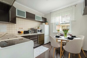 Moderni keittiö, jossa on sisäänrakennettu mikroaaltouuni, pesuallas ja ruokailutila, jossa on pöytä kahdelle.