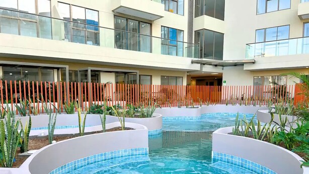 A modern hotel courtyard with a central swimming pool, surrounded by planters and a wooden fence. - 2-bedroom apartment with Lake views and a heated pool in Nakuru Town (Nakuru)