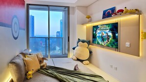 Een moderne woonkamer met een bank, een grote televisie en uitzicht op de stad.