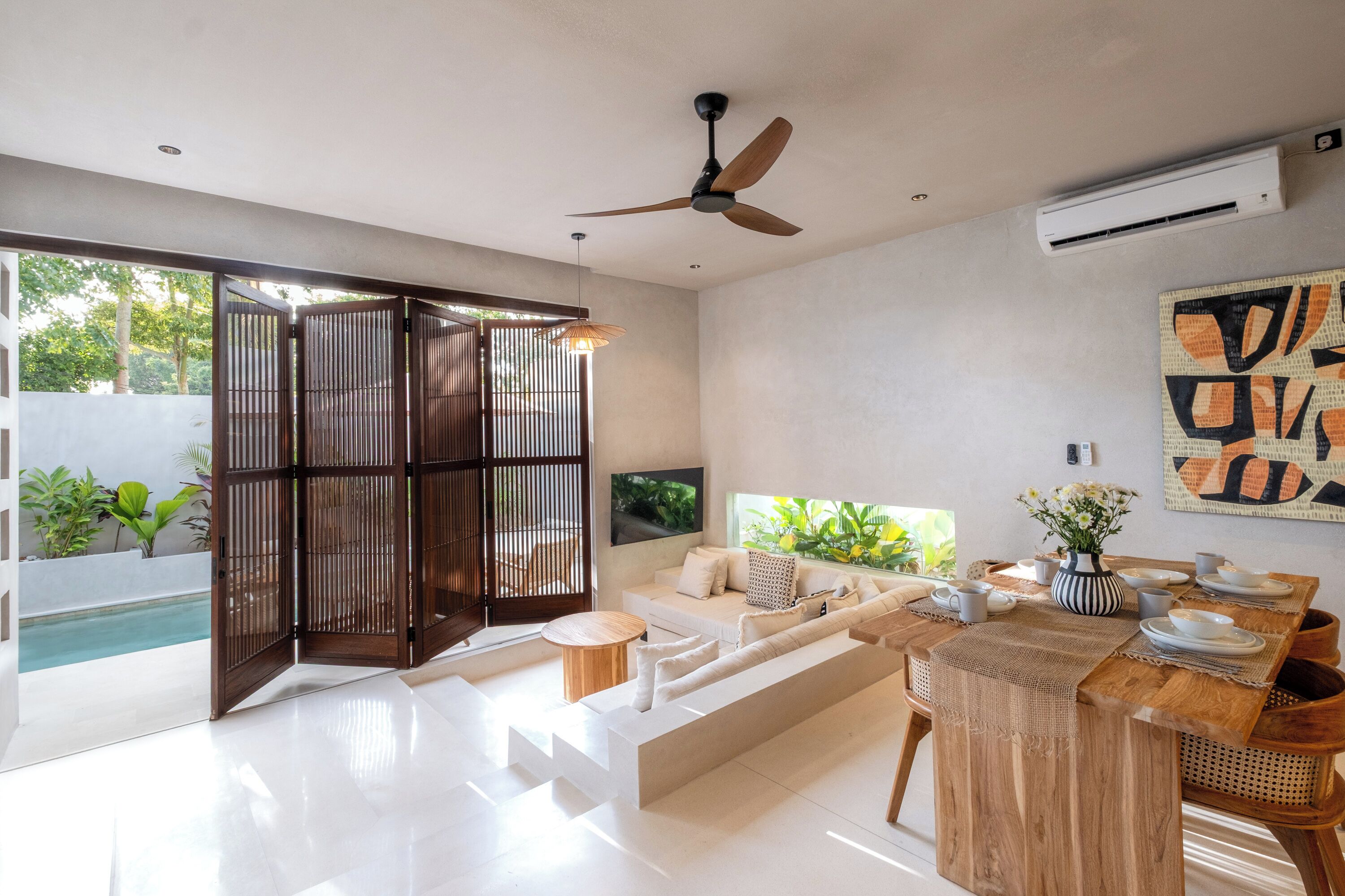 A modern living room with a sofa, dining table, and a ceiling fan.