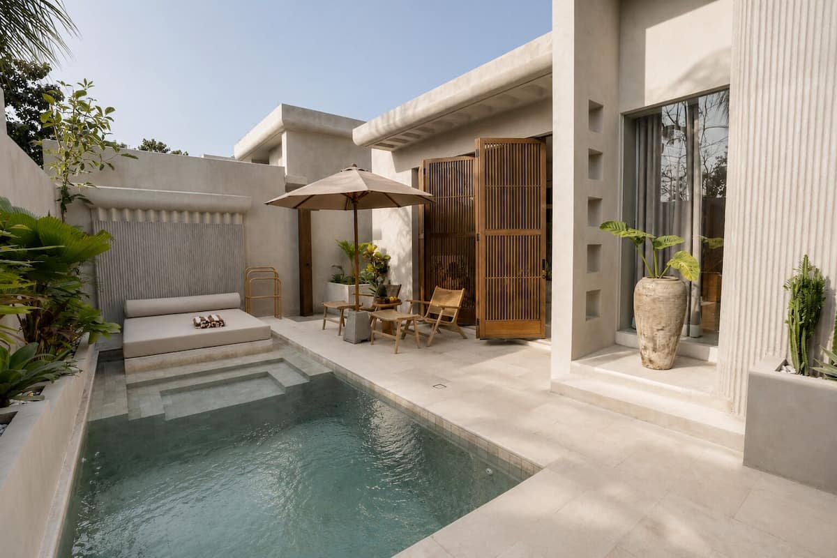 A modern outdoor pool area with a seating arrangement and a large umbrella.
