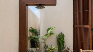 Een moderne buitendouche met een houten frame, omgeven door verschillende planten.