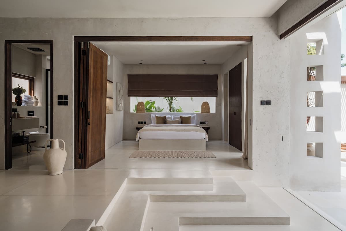 A modern bedroom with a large bed, a bedside table, and a window with a view.
