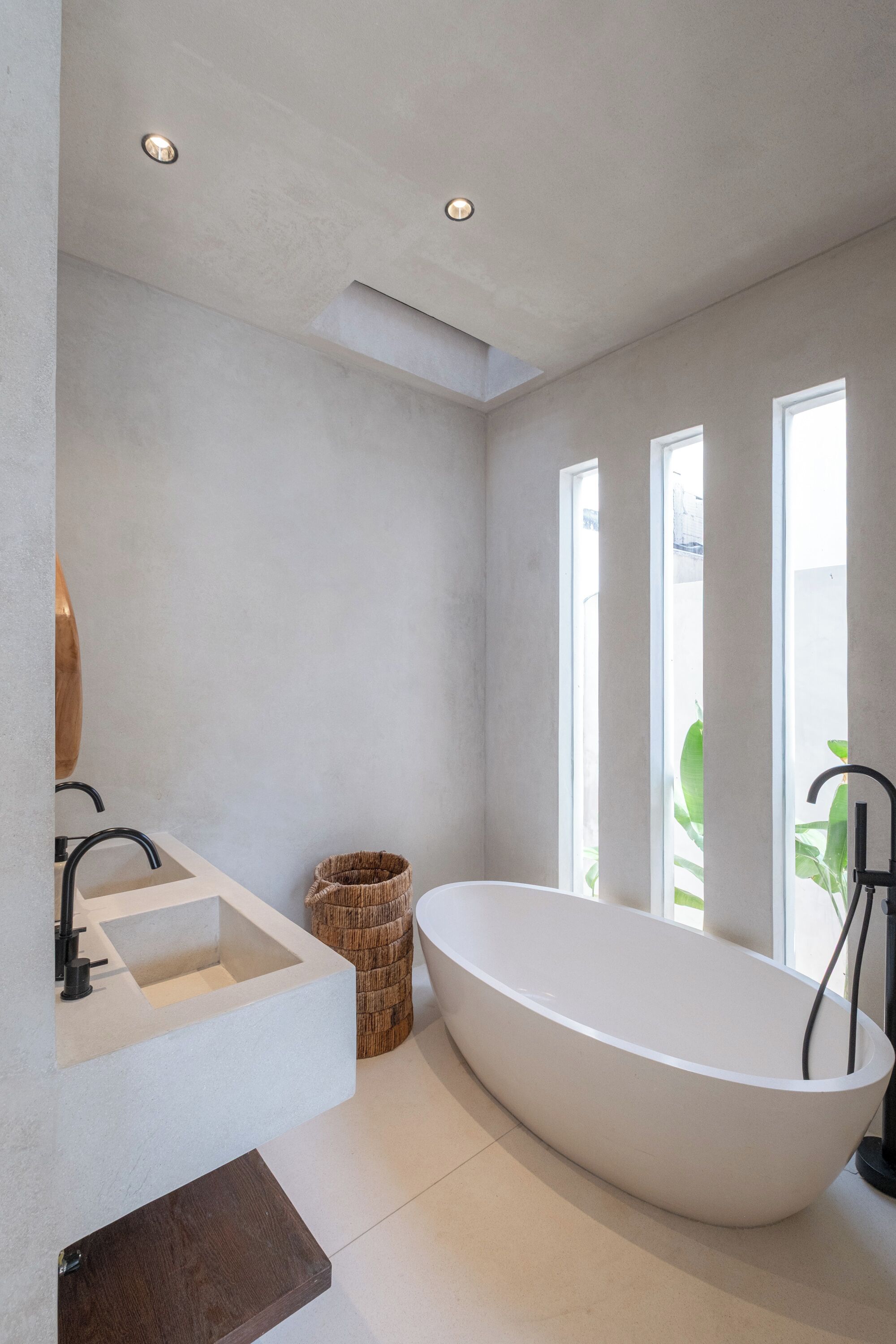 A modern bathroom with a freestanding bathtub, a built-in sink, and a large window providing natural light.