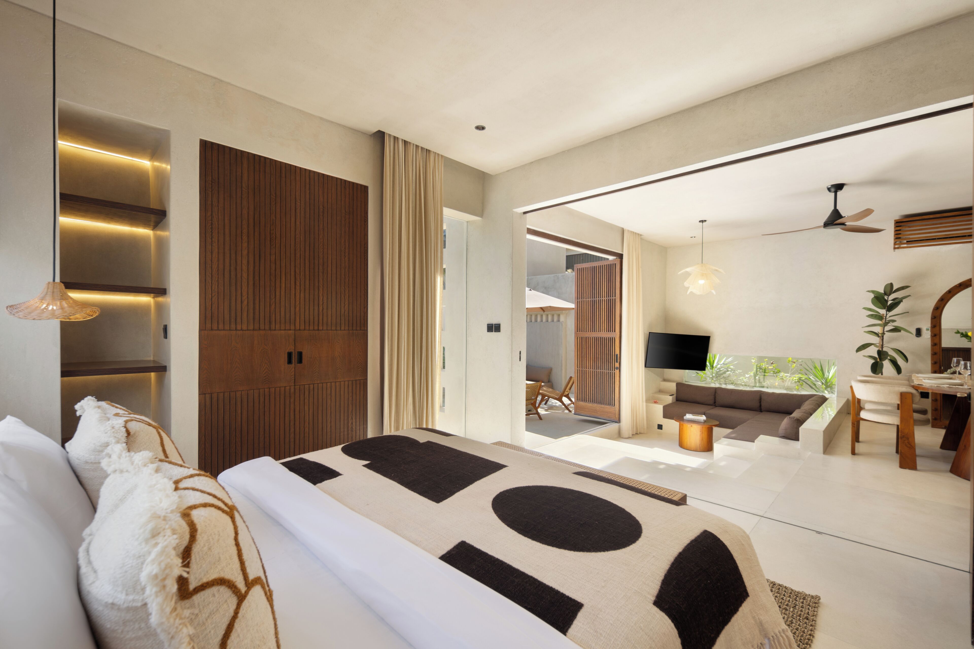 Una moderna camera d'albergo con un letto grande, una zona salotto con divano e poltrone, un tavolo da pranzo e una televisione.
