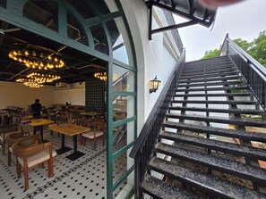 Een restaurantinterieur met een trap die leidt naar een terras.