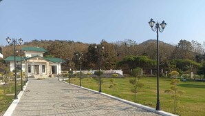 Un chemin pavé mène à un bâtiment doté d’un toit végétalisé, lequel est entouré d’un espace paysager agrémenté d’arbres et de lampadaires.