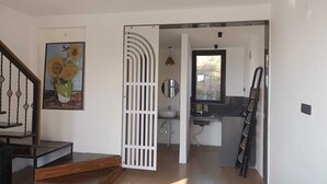 Un intérieur moderne avec un escalier, un tableau de tournesols, un coin cuisine et une échelle.