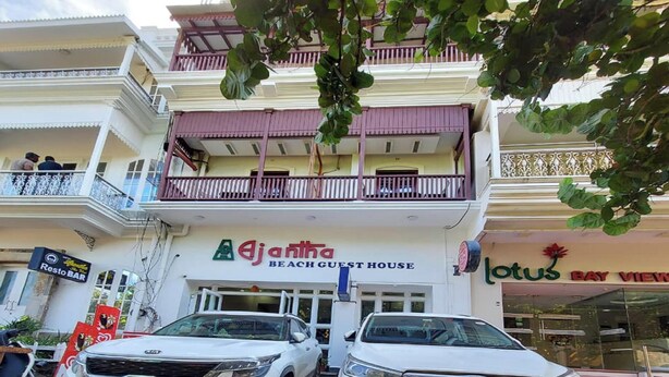 A two-story building with a sign for 'Ajantha Beach Guest House'. Two white SUVs are parked in front. - Ajantha Guest House (Puducherry)