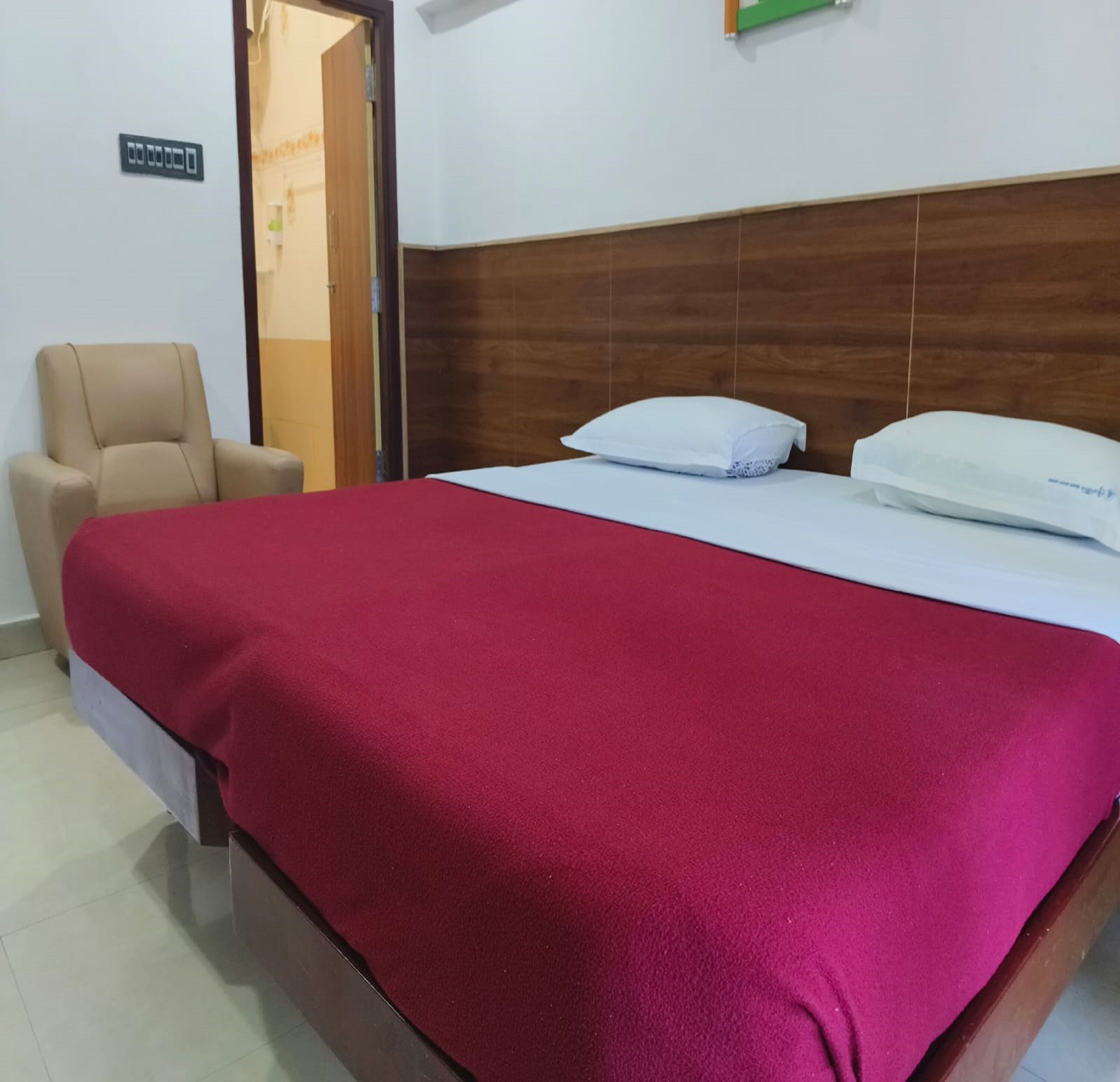 Une chambre d’hôtel avec un lit, une chaise et une tête de lit en bois.