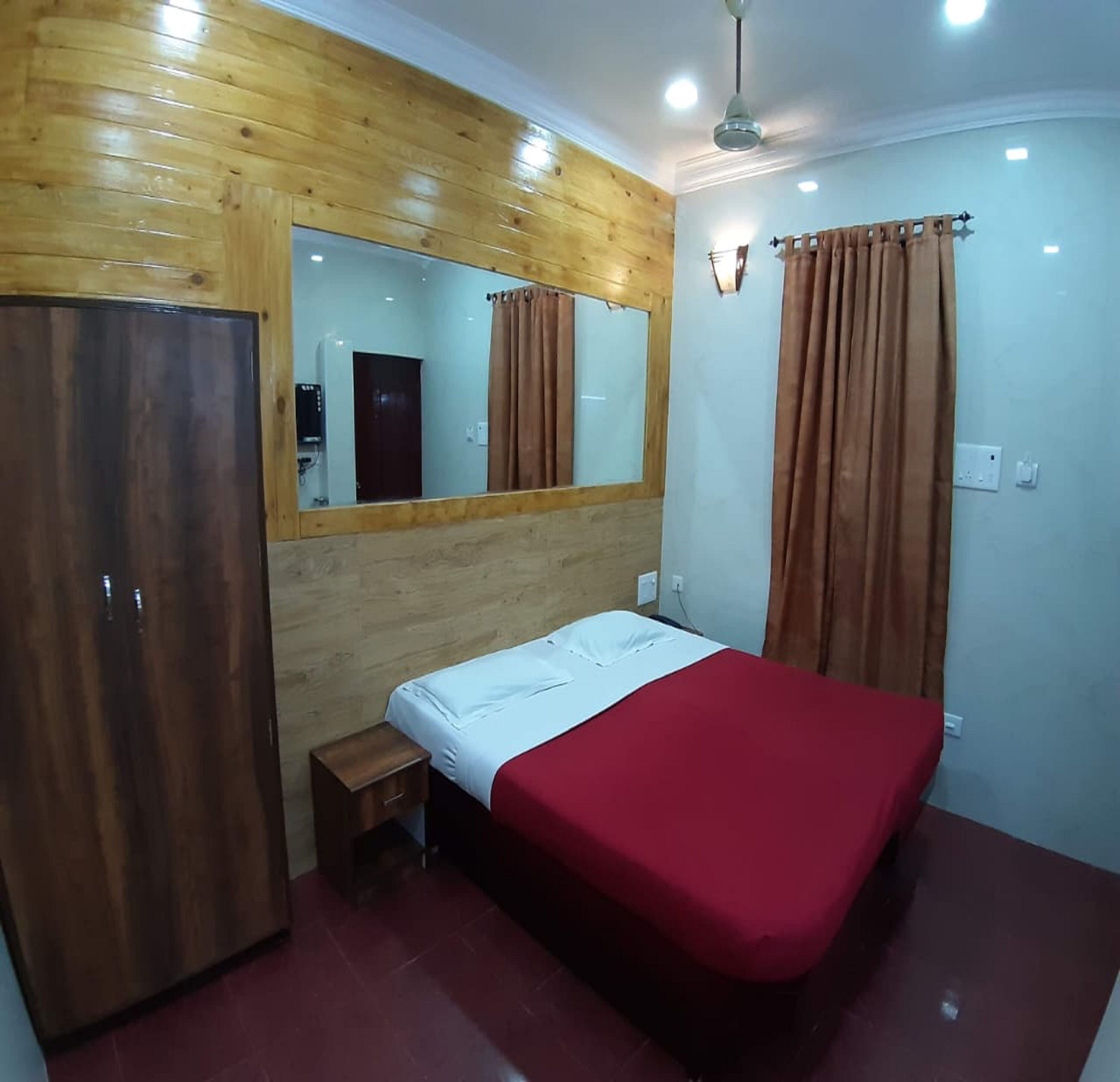 A room with a bed, a wardrobe, a mirror, and a ceiling fan.