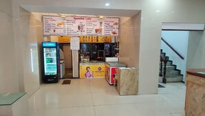 A cafe with a menu board, a Pepsi refrigerator, and a counter. - Ajantha Guest House (Puducherry)
