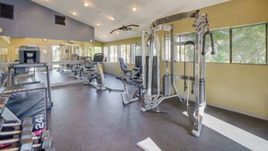 Ein Fitnessstudio mit unterschiedlichen Trainingsgeräten, darunter Laufbänder, Kraftgeräte und ein Kabelzuggerät.