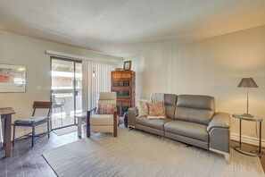 A living room with a sofa, armchair, and a small table. There is a bookshelf and a lamp. - 3 Mi to Camelback Mtn! Snowbird Escape w/ Pool (Phoenix)